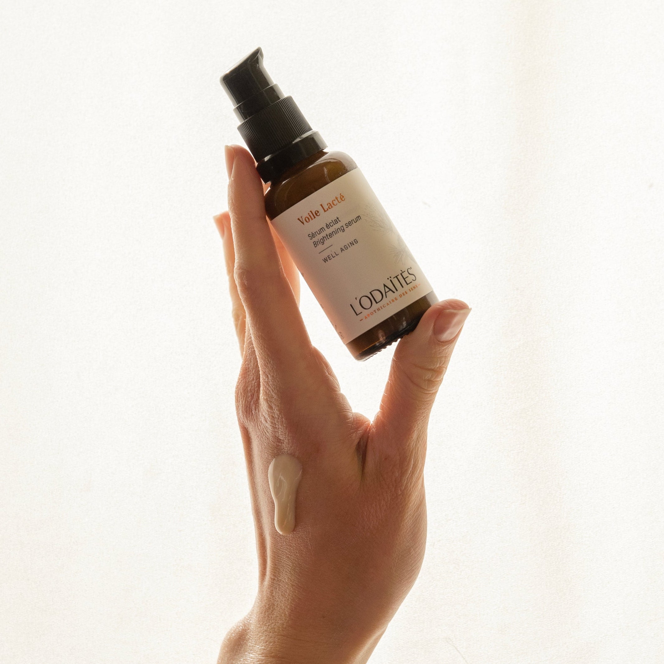 Hand holding L'Odaïtès brightening serum with a drop of texture